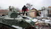 Người dân địa phương trên một xe thiết giáp Nga bị vô hiệu hóa tại Ukraine, ngày 1/3/2022 - Ảnh: Serhii Nuzhnenko (Reuters)