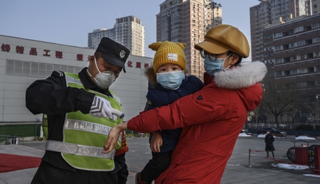 Kiểm tra thân nhiệt một phụ nữ Trung Quốc trước khi đưa con vào công viên. Bắc Kinh, ngày 9-2-2020 - Ảnh: Kevin Frayer
