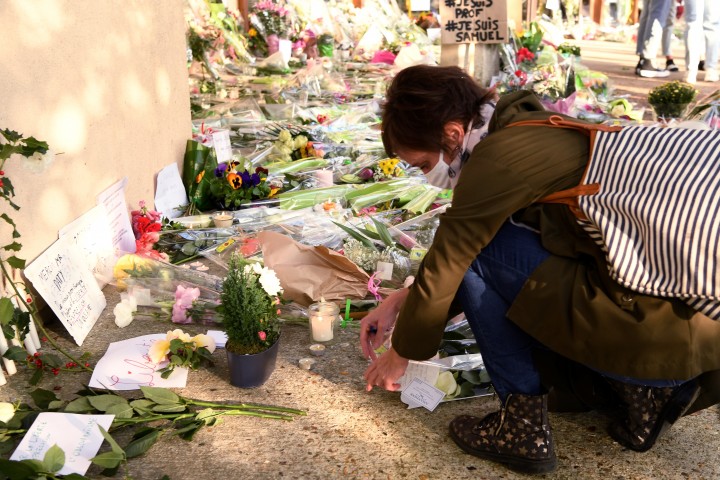 Một phụ nữ đặt hoa tại trường của nhà giáo Samuel Paty đã bị sát hại dã man, ngày 17/10/2020 - Ảnh: Bertrand Guay (AFP)