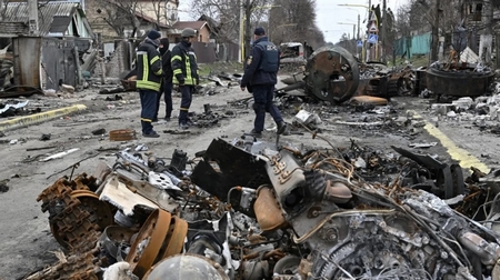 Kiểm tra các phương tiện bị phá hủy trên đường phố Bucha ngày 5/4/2022 - Ảnh: Genya Salilov (AFP)