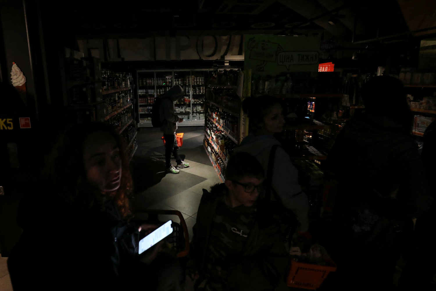 Người mua hàng tại một tiệm thực phẩm bị cắt điện do chiến tranh ở Lviv - Ảnh: Roman Baluk (Reuters)